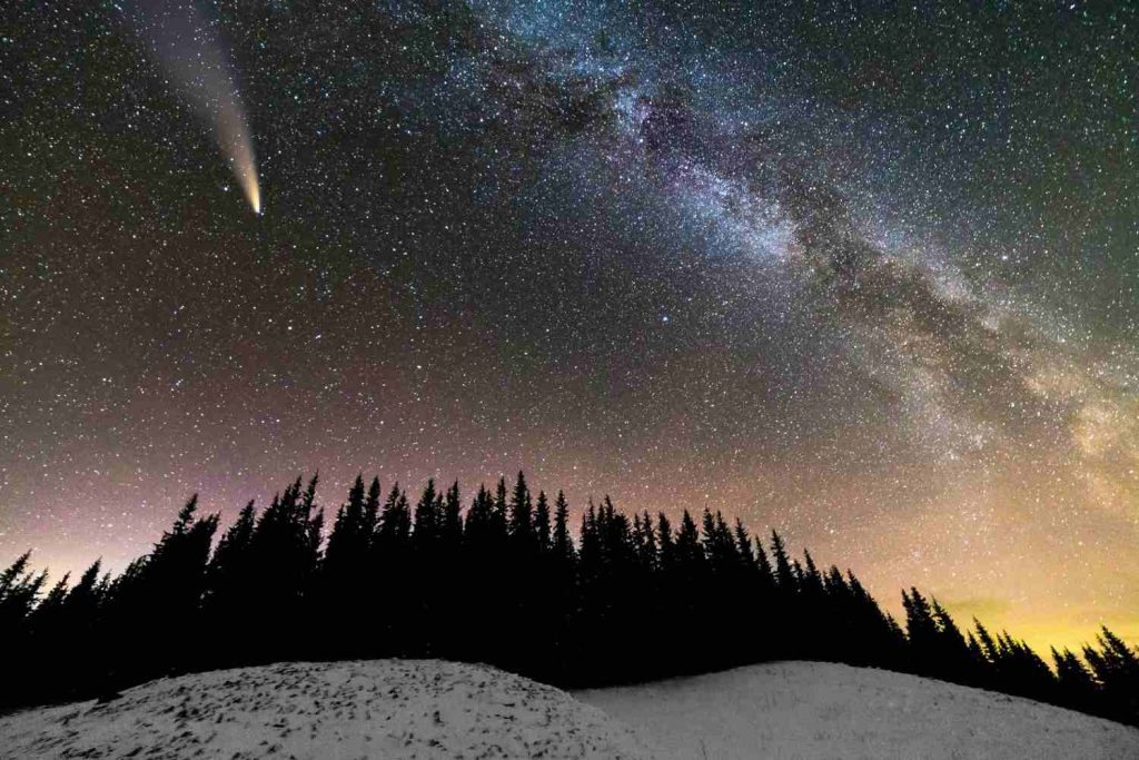 Comet and Milky Way galaxy over snowy pine forest, reflecting Volant Legacy's space exploration themes